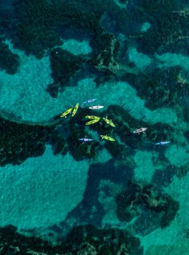 Um grupo de pessoas pratica caiaque nas águas cristalinas do Mediterrâneo, em Ibiza.