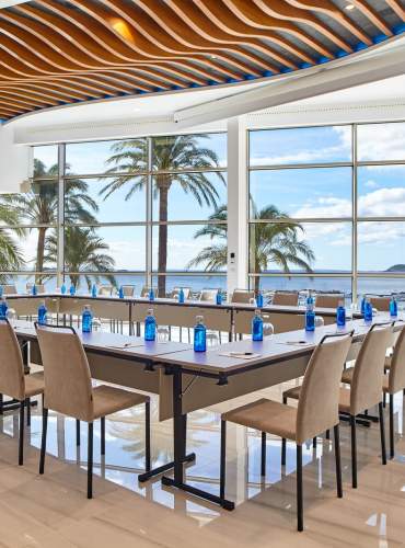 Espaço para reuniões e eventos com amplas janelas e vista para o Mar Mediterrâneo. Equipado para conferências e encontros profissionais, o espaço combina design contemporâneo, abundante luz natural e um ambiente costeiro rodeado de palmeiras, representando a oferta de eventos MICE de Ibiza.