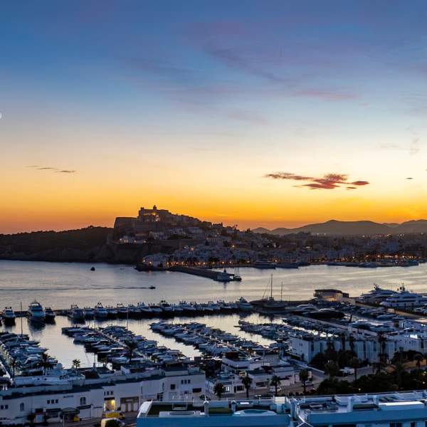 Um casal tira uma selfie junto à placa de Ibiza-Eivissa, com Dalt Vila ao fundo.