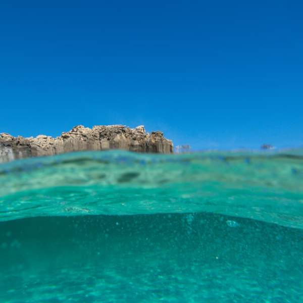 O Mar Mediterrâneo visto de dentro, com as suas águas turquesas e transparentes, sob um céu azul límpido.
