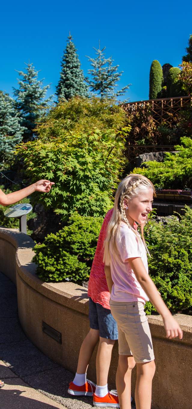A family of four looks happily at the outdoor train display.
