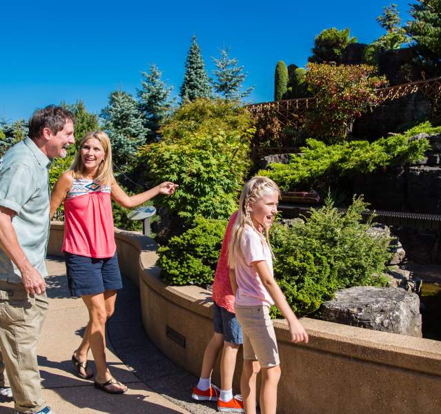 A family of four looks happily at the outdoor train display.