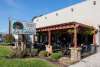 A stucco building with a fenced in patio sits near grass. The sky is blue. A sign out front reads La Cabaña and Mexican Restaurant and Cantina