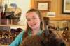 A young girl in a turquoise shirt holds a large bison stuffed animal