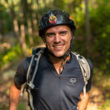 A man in a bike helmet smiles at the camera.