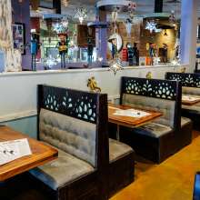 Black booths with gray seats  line up along a half wall. Mexican art lines the wall and decorations hang from the ceiling.