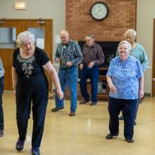 A group of seniors is doing a line dance