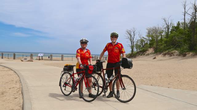 Bicyclists dress in red stand with their bikes on a walkway in the Indiana Dunes State park.