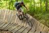 A man wearing a helmet rides a mountain bike on a wooden raised trail