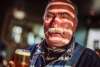 An older man with a curled mustache holds a glass of beer.