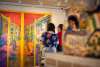 Two people look at a brightly colored painting on the wall. A blurred statue is in the foreground.