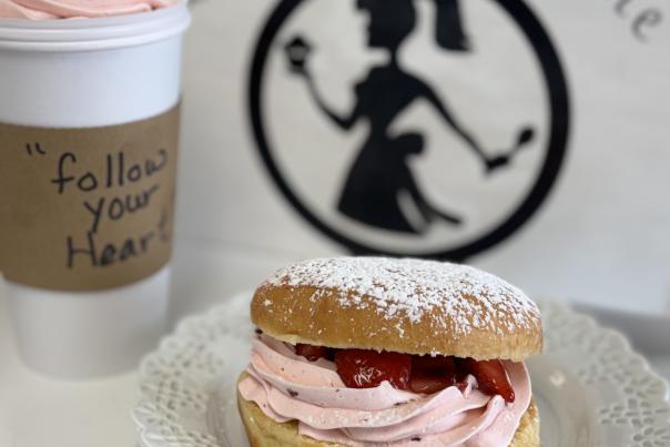 Fresh strawberry cream doughnut dusted with powdered sugar alongside a pink whipped specialty beverage on the Indiana Dunes Coffee & Sweets Trail.