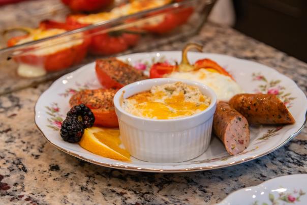 A quiche, sausage, veggies, and fruit on a plate