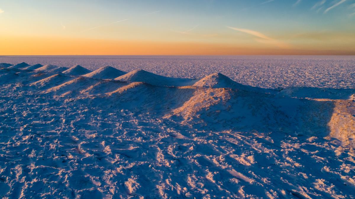 Shelf ice under a gradient sky from orange to blue at sunset.