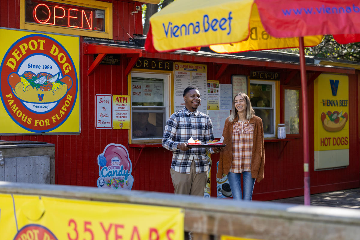 Two people enjoying hot dogs outside Depot Hot Dogs, a longtime local restaurant in Portage, Indiana.
