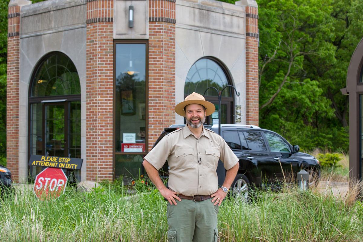 A park ranger stands in front of a brick entrance building.