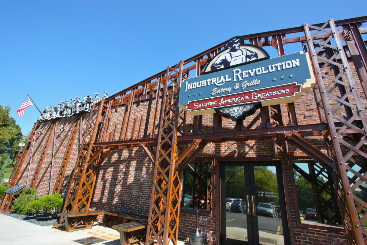 The front of a restaurant is designed to look like an industrial construction project with statues of works on the roof.