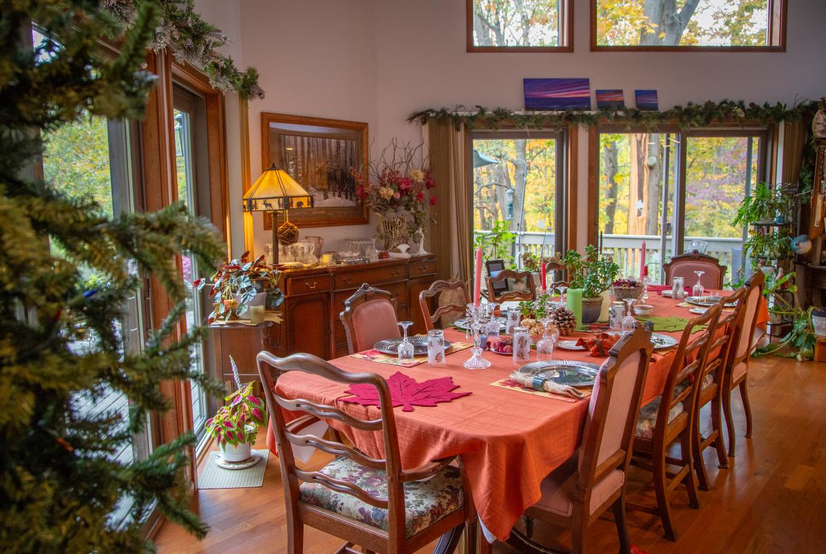 A dining room has a long dining table with a peach tablecloth. The table is set for a meal.