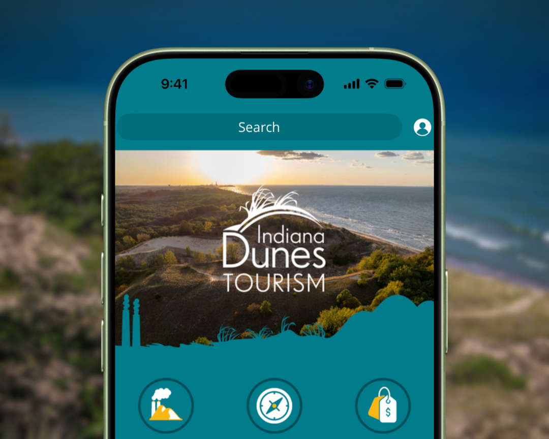 Smartphone displaying the Indiana Dunes Tourism app with Lake Michigan dunes in the background.
