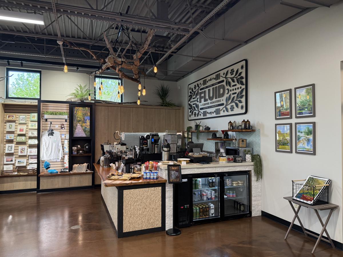 FLUID Coffeebar inside the Beaches & Beyond Gift Shop at the Indiana Dunes Visitor Center, with coffee counter, Indiana Dunes merchandise, and local artwork displays.