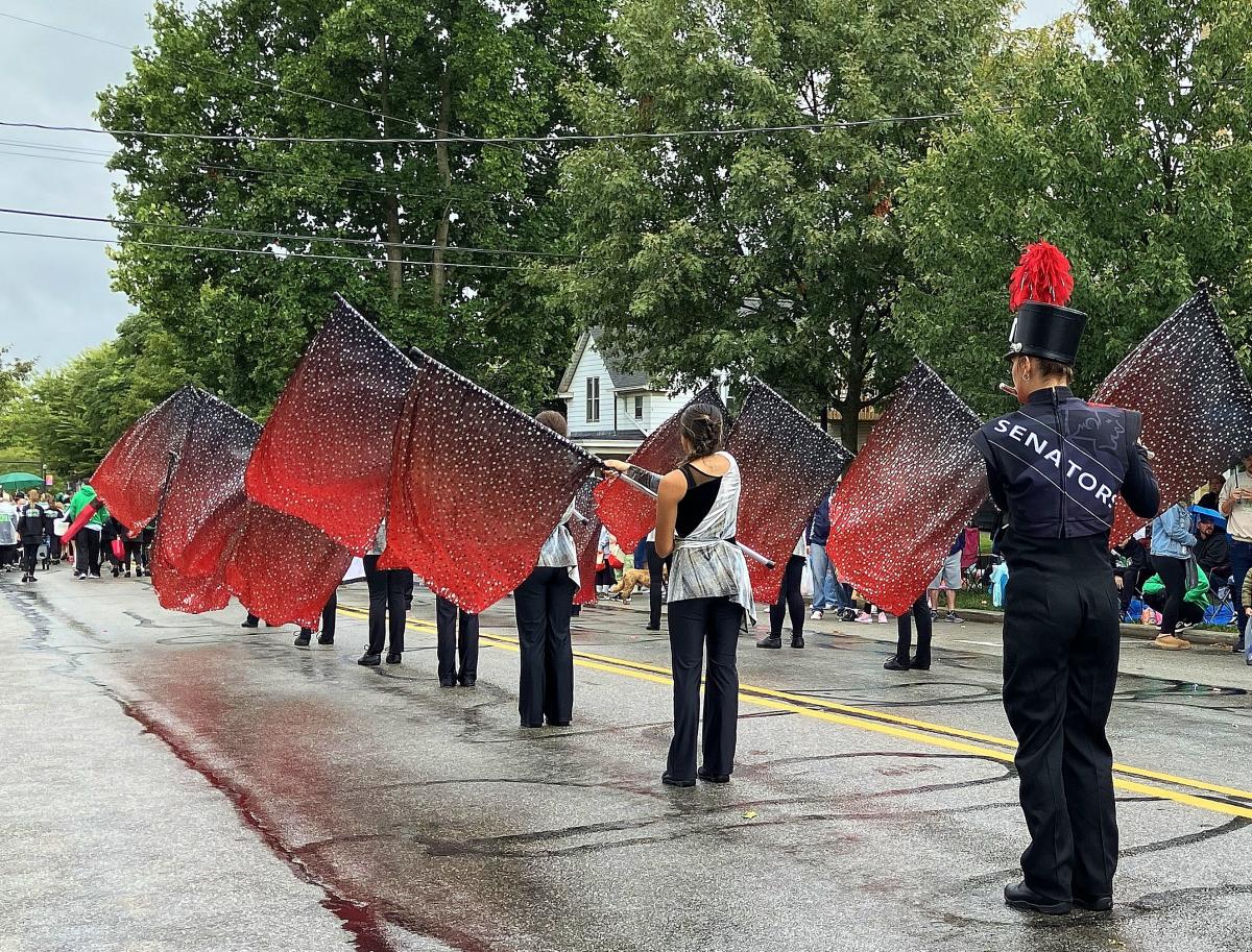 Parade participants hold red and black flags.