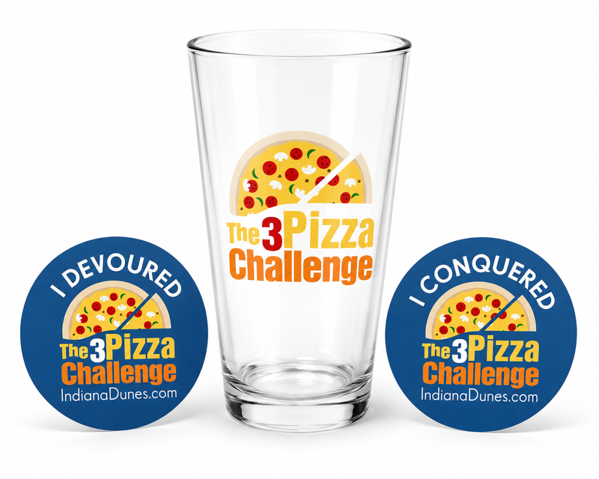 A pub glass with the logo for The 3 Dune Challenge and two stickers for the challenge.