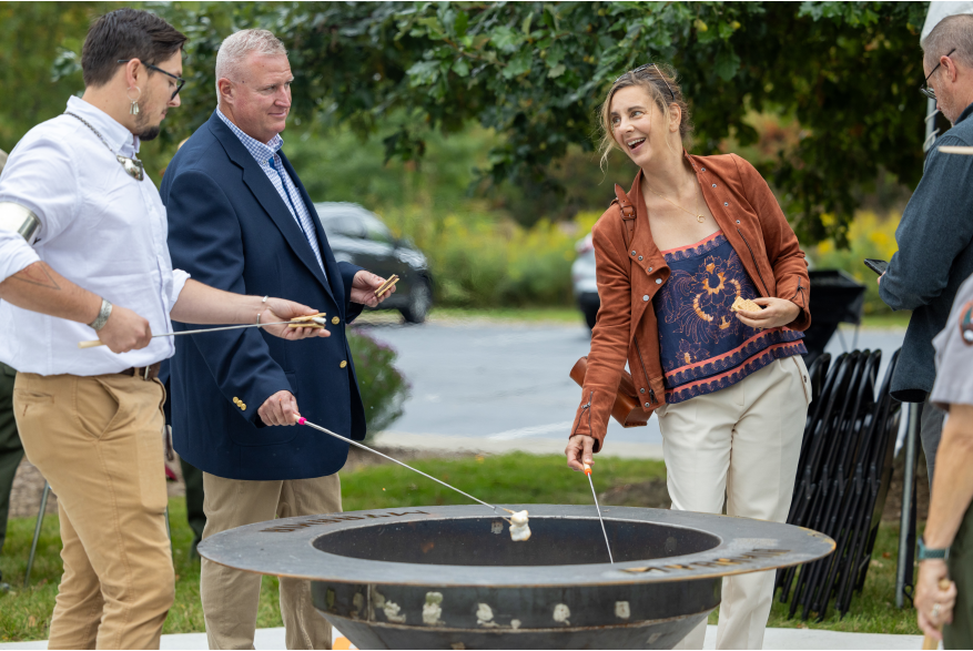 People roast marshmallows over a low firepit.