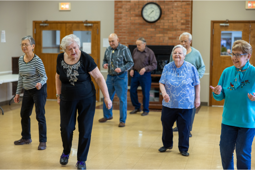 A group of seniors is doing a line dance