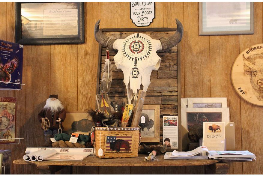 A decorated bison skull hangs on the wall. A table below it holds various bison products.