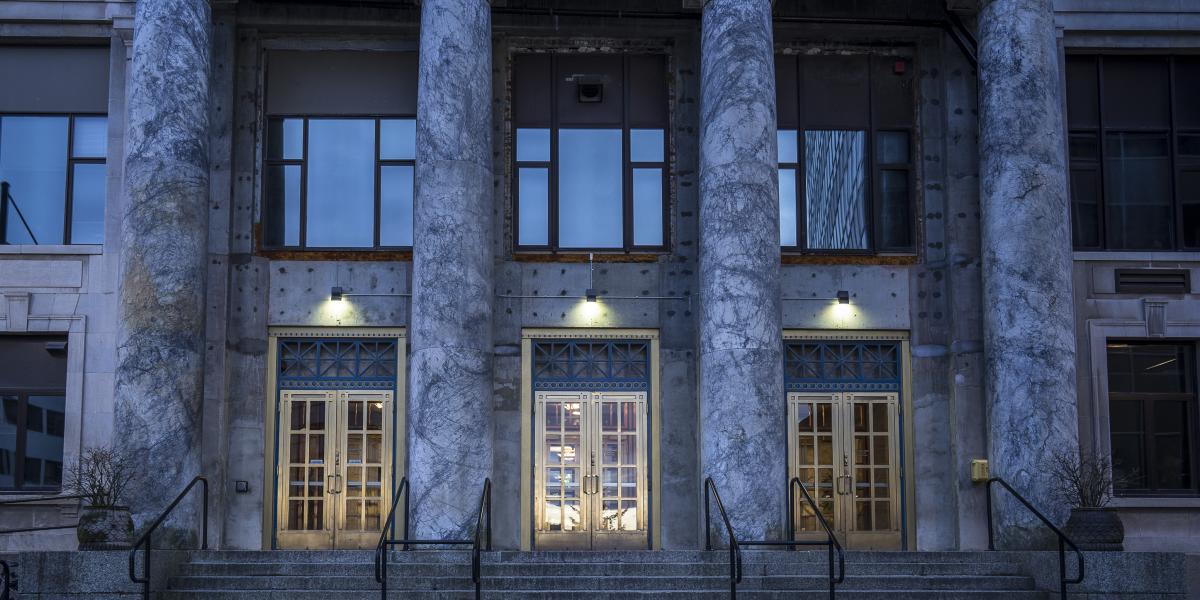 The stunning front entrance of the Juneau Capitol building with marble pillars and golden doors.