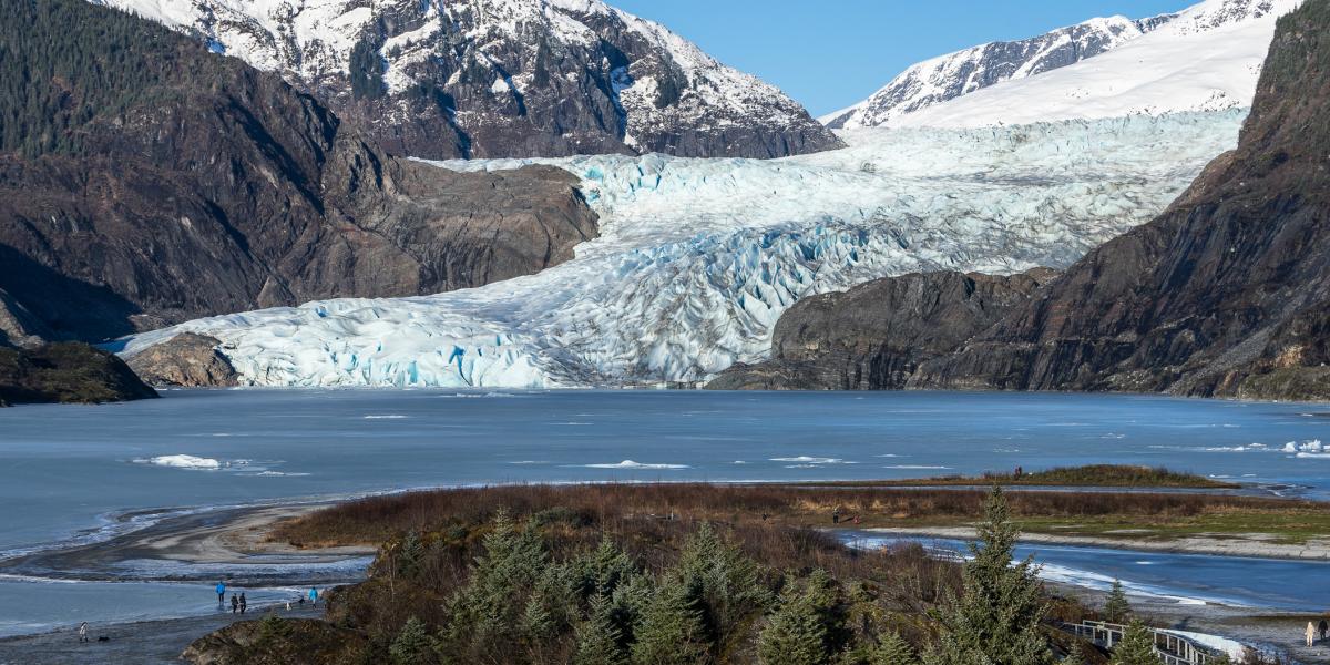 A stunning view of Mendenhall Glacier surrounded by the calm waters of Mendenhall Lake.