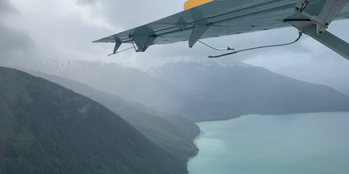 An aerial view of the green, tree-filled mountains and icy blue waters in Juneau, Alaska