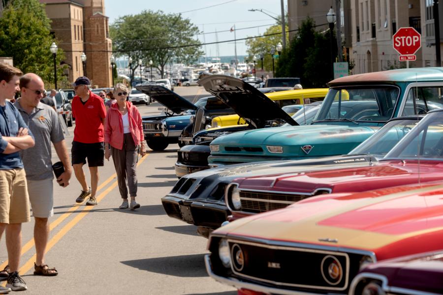 Classic cars with open hoods lining a street during the Kenosha Classic Cruise-In