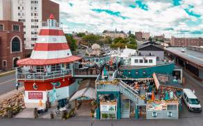Cooper's Seafood House restaurant with a lighthouse and pirate ship design, featuring outdoor seating, decorations, and a large octopus sculpture on the top deck.