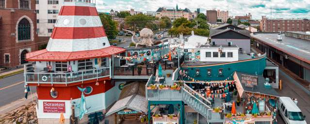Cooper's Seafood House restaurant with a lighthouse and pirate ship design, featuring outdoor seating, decorations, and a large octopus sculpture on the top deck.
