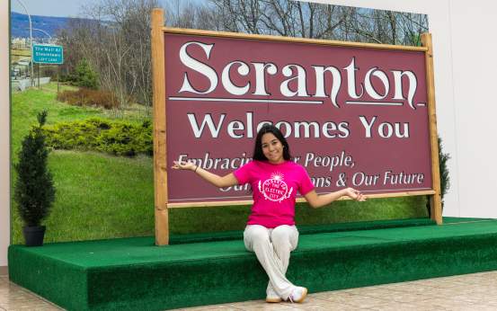 Woman posing for a pic in front of the Scranton Welcomes You Sign in Downtown Scranton, PA