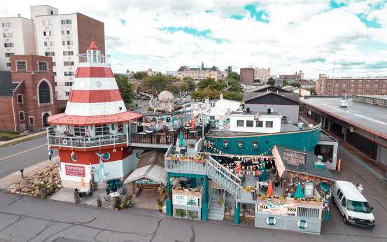 Colorful Cooper's Seafood House restaurant with a lighthouse design, featuring outdoor seating, decorations, and a large octopus sculpture nearby.