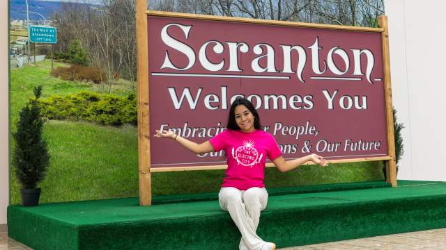 Woman posing for a pic in front of the Scranton Welcomes You Sign in Downtown Scranton, PA