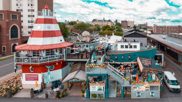 Cooper's Seafood House restaurant with a lighthouse and pirate ship design, featuring outdoor seating, decorations, and a large octopus sculpture on the top deck.