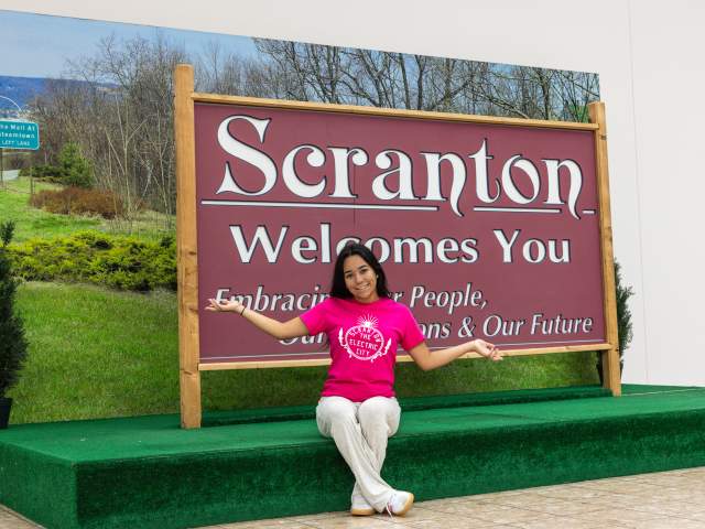 Woman posing for a pic in front of the Scranton Welcomes You Sign in Downtown Scranton, PA