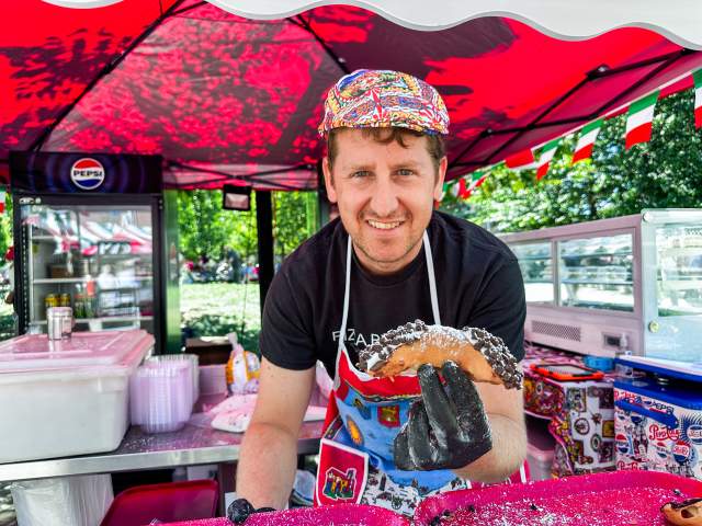 Man holding a cannoli at a food booth at La Festa Italiana in Downtown Scranton