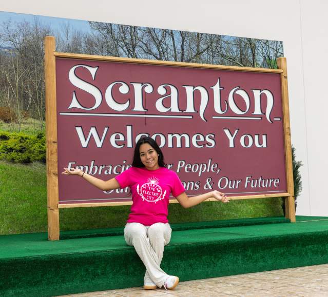 Woman posing for a pic in front of the Scranton Welcomes You Sign in Downtown Scranton, PA