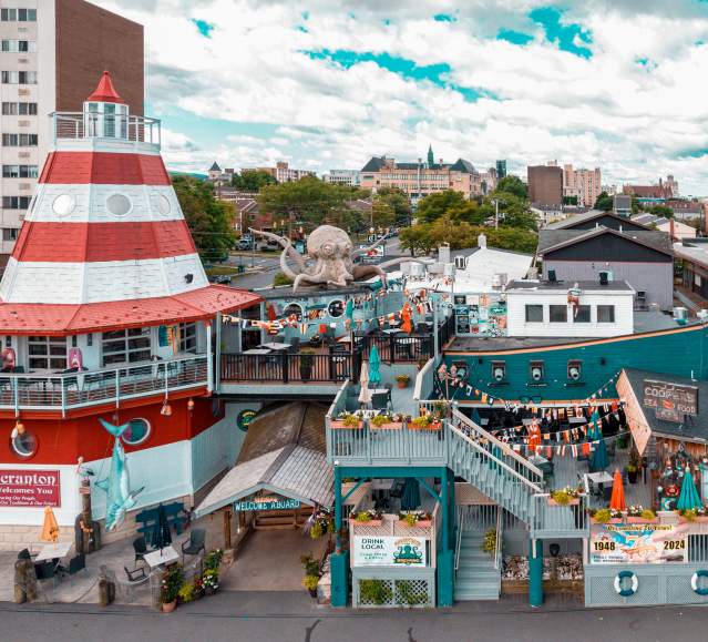 Cooper's Seafood House restaurant with a lighthouse and pirate ship design, featuring outdoor seating, decorations, and a large octopus sculpture on the top deck.