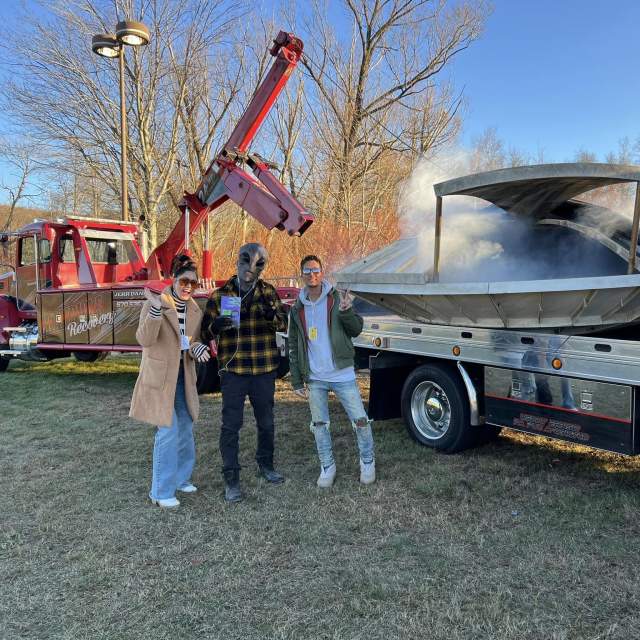 A woman and man posing for a photo in front of a "UFO" alongside a man dressed as an alien at the Carbondalien Festival in Carbondale, PA