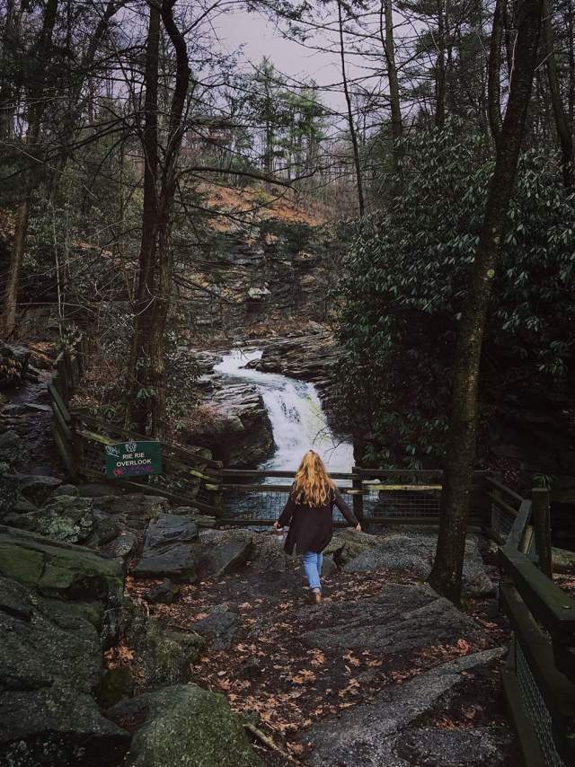 Woman walking on hiking trail overlooking the waterfall at Nay Aug Parkk in Scranton, PA