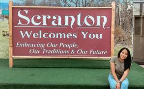 woman sitting in front of Scranton Welcomes You Sign in Downtown Scranton, PA