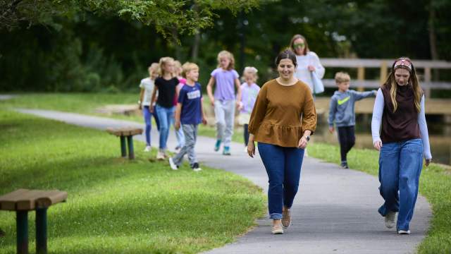 A group of people walking on a paved path through McDade Park in Scranton, PA