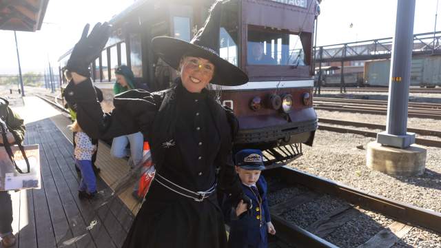 A costumed witch waves beside a child dressed as a conductor in front of a vintage trolley at the Electric City Trolley Museum in Scranton, PA.