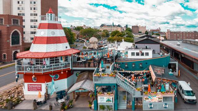 Cooper's Seafood House restaurant with a lighthouse and pirate ship design, featuring outdoor seating, decorations, and a large octopus sculpture on the top deck.