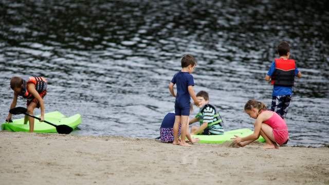Children sitting in the sand beside the pond at Covington Park in Covington Township, PA
